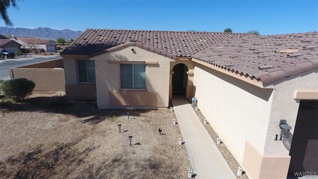 view of front facade featuring a tiled roof, a mountain view, and stucco siding