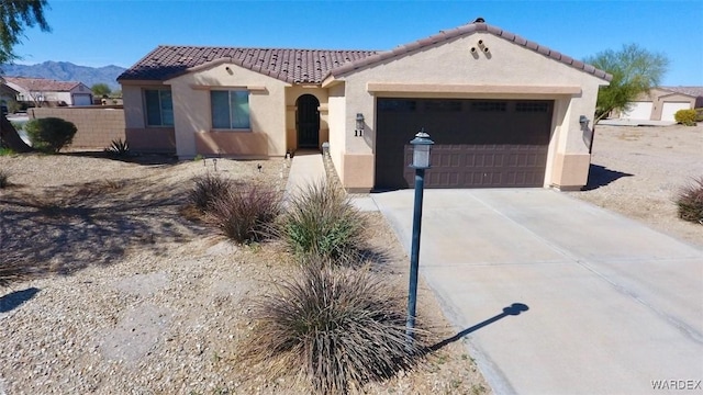 view of front of house featuring concrete driveway, a tiled roof, an attached garage, and stucco siding