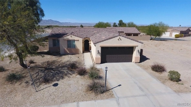 view of front of home with driveway, stucco siding, a garage, a tiled roof, and a mountain view