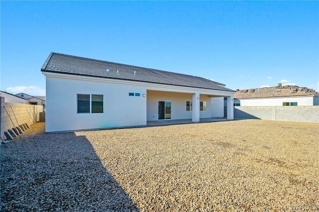 back of property with a fenced backyard, a patio, and stucco siding