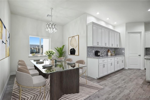 kitchen with light wood-style floors, white cabinetry, and pendant lighting