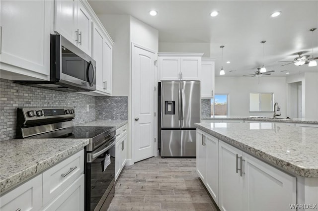 kitchen featuring white cabinets, appliances with stainless steel finishes, backsplash, pendant lighting, and a sink