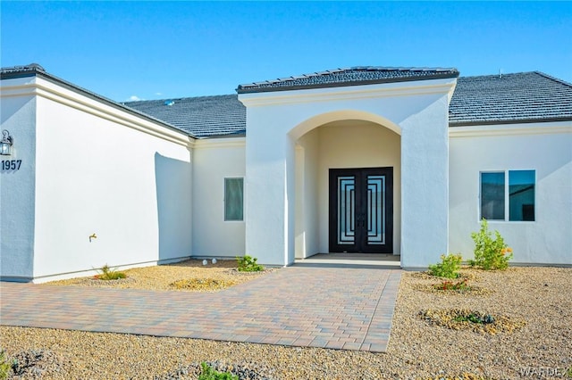 view of exterior entry with a tile roof and stucco siding