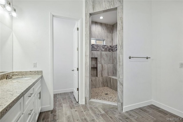 bathroom featuring baseboards, a walk in shower, vanity, and wood tiled floor