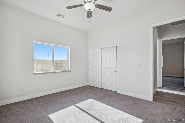 unfurnished bedroom with baseboards, visible vents, and dark carpet