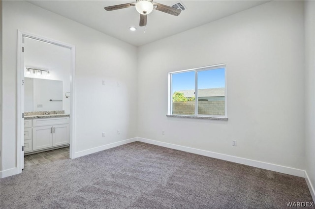 unfurnished bedroom with light carpet, a sink, visible vents, baseboards, and ensuite bath