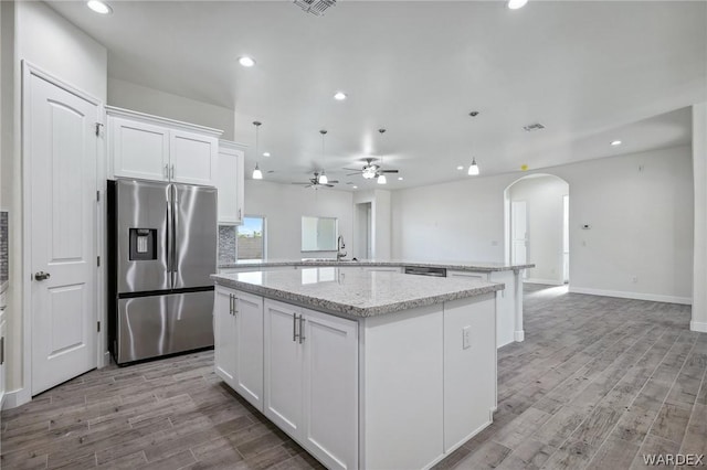 kitchen with open floor plan, stainless steel fridge, a center island, and white cabinets