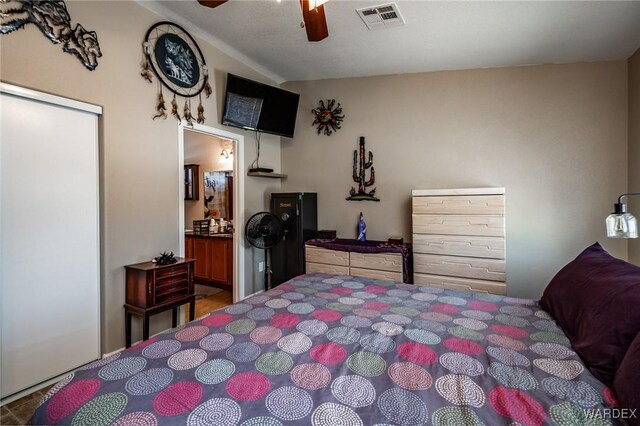 bedroom with ensuite bath, visible vents, and a ceiling fan