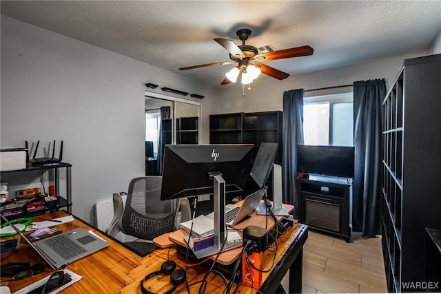 office area with ceiling fan, light wood finished floors, and a textured ceiling