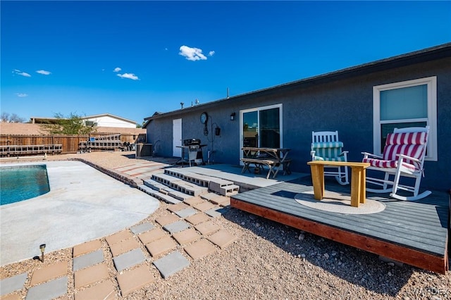 back of property with cooling unit, fence, a wooden deck, a fenced in pool, and stucco siding