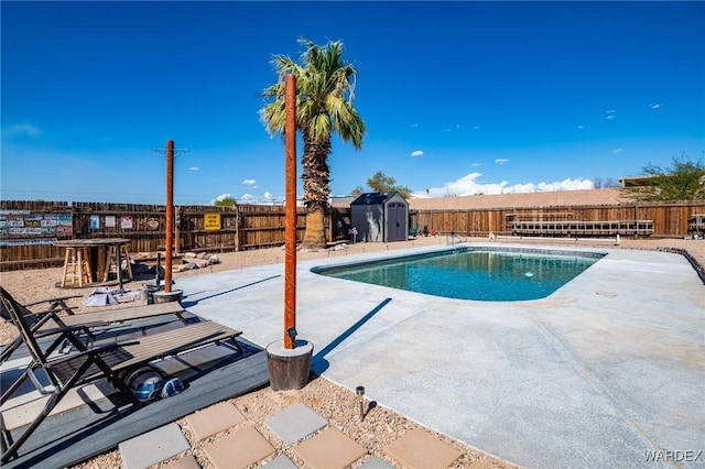 view of pool featuring an outbuilding, a fenced backyard, a storage shed, a fenced in pool, and a patio area