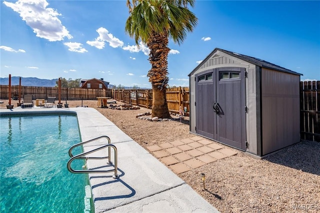 view of pool with a fenced in pool, an outbuilding, a mountain view, a shed, and a fenced backyard