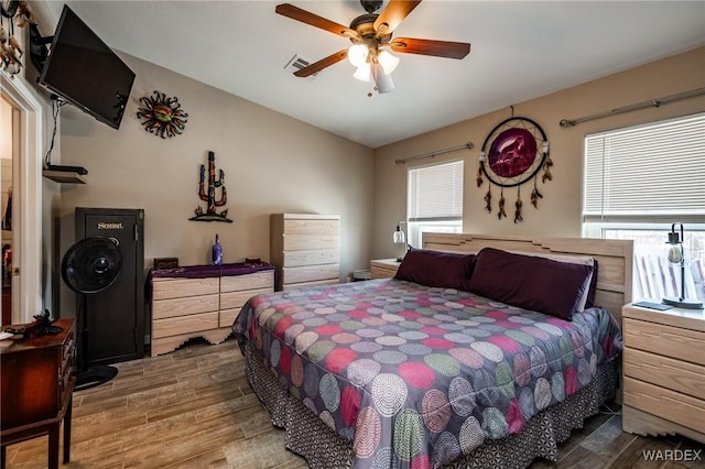 bedroom featuring visible vents, a ceiling fan, vaulted ceiling, and wood finished floors