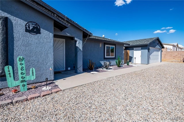 view of front of home with fence, an outbuilding, and stucco siding