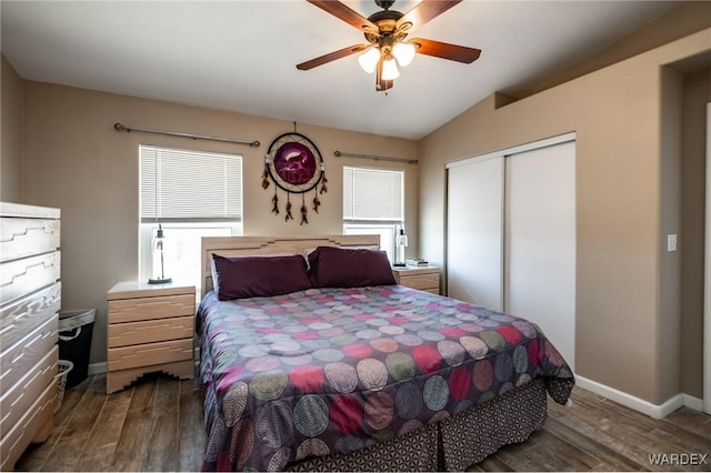 bedroom with dark wood-style floors, a closet, vaulted ceiling, and baseboards