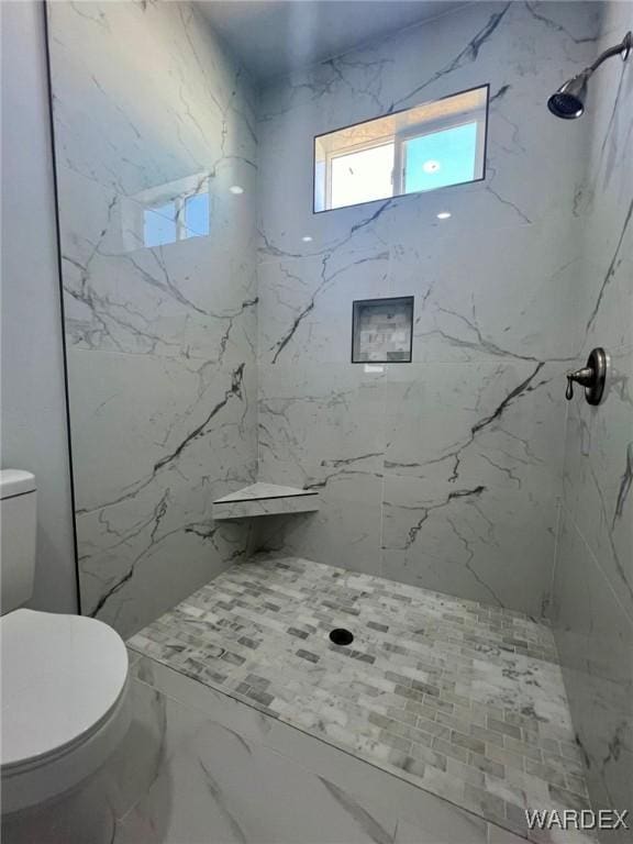 bathroom with toilet and a marble finish shower