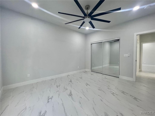 unfurnished bedroom featuring ceiling fan, marble finish floor, a closet, and baseboards