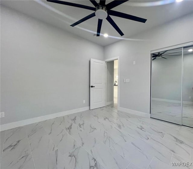 unfurnished room with marble finish floor, ceiling fan, and baseboards