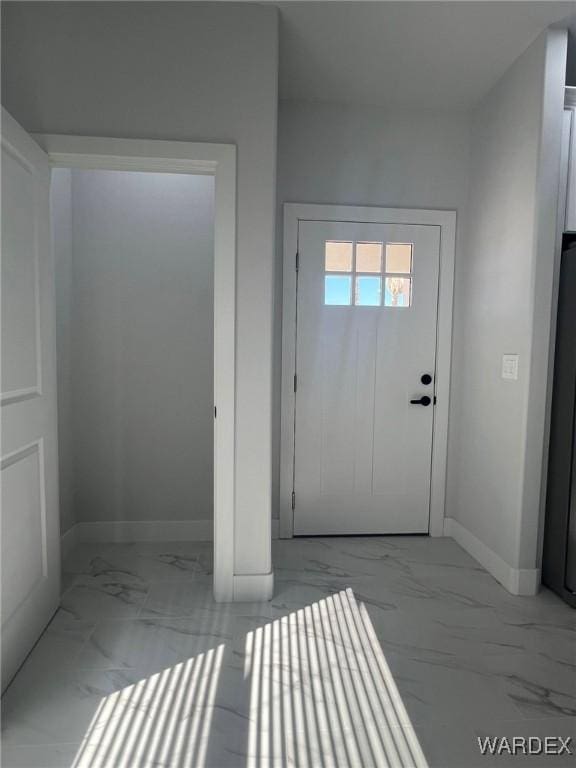 doorway to outside with marble finish floor and baseboards