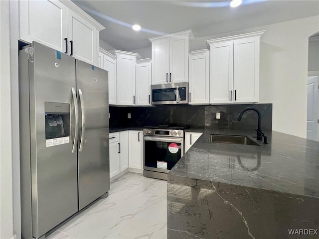 kitchen with marble finish floor, decorative backsplash, appliances with stainless steel finishes, white cabinetry, and a sink