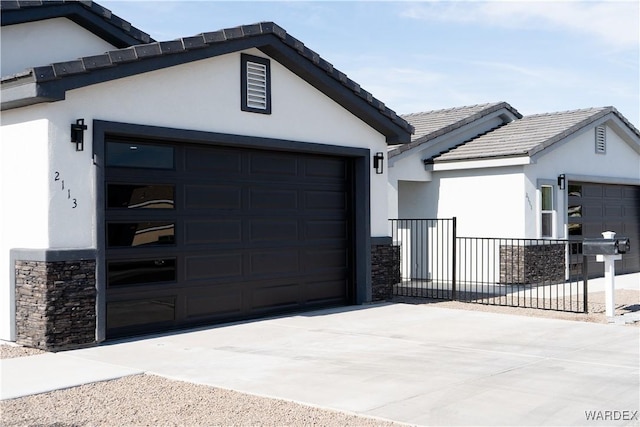 view of front facade with an attached garage, stone siding, concrete driveway, and stucco siding