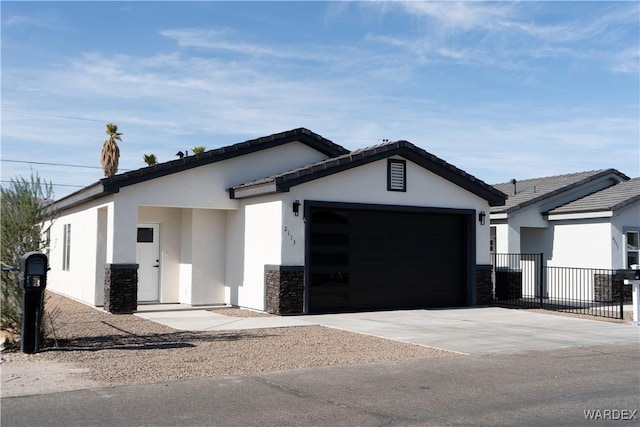 view of front facade featuring a garage, driveway, stone siding, fence, and stucco siding