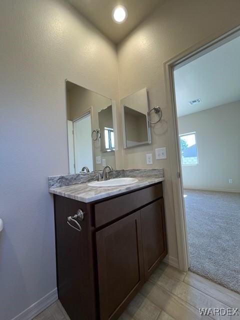 half bath featuring visible vents, baseboards, and vanity