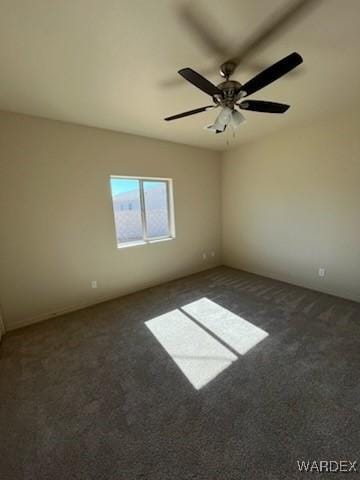 spare room with ceiling fan and dark carpet