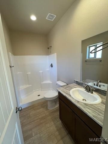 bathroom featuring visible vents, a shower, toilet, wood finished floors, and vanity