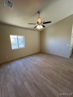 empty room with wood finished floors, visible vents, and a ceiling fan