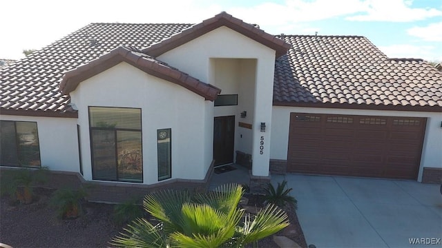 view of front of property featuring a tile roof, driveway, an attached garage, and stucco siding