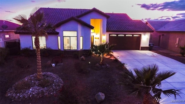 view of front of property featuring a garage, stucco siding, concrete driveway, and a tiled roof