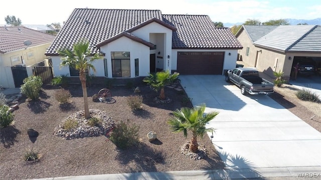 view of front of home featuring a garage, driveway, a tile roof, and stucco siding