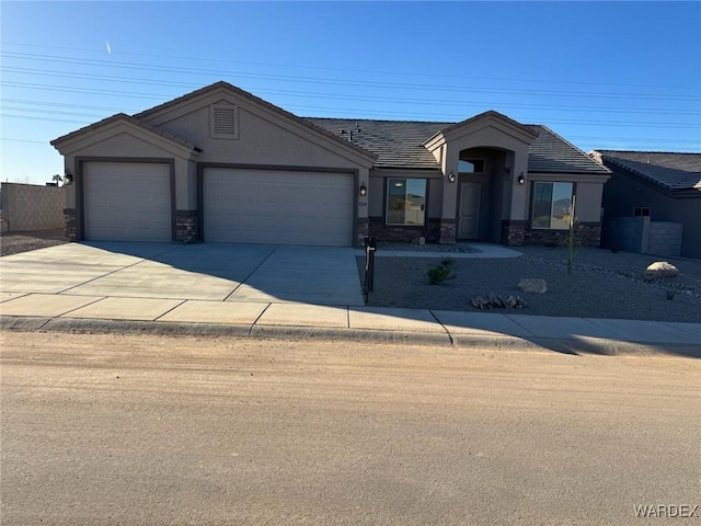 view of front of home with a garage, concrete driveway, stone siding, a tile roof, and stucco siding