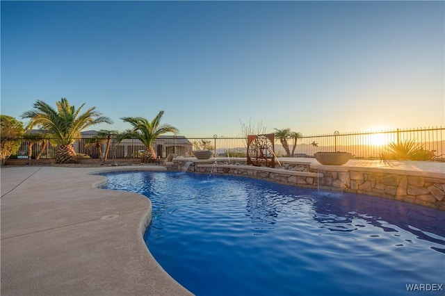 pool at dusk with a fenced in pool, a fenced backyard, and a patio