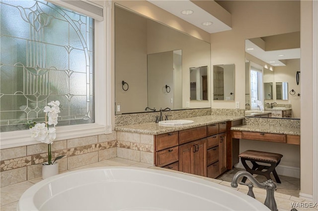 full bath featuring a washtub, vanity, and tile patterned floors