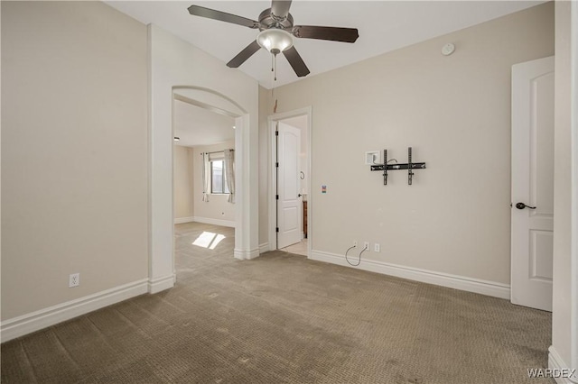 carpeted empty room featuring ceiling fan and baseboards