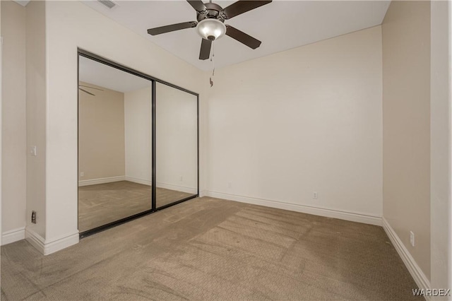 unfurnished bedroom with carpet, baseboards, ceiling fan, and a closet