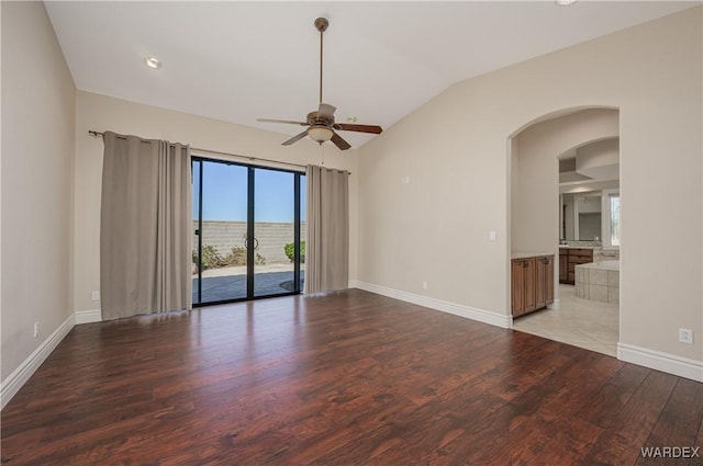 unfurnished room featuring arched walkways, baseboards, a ceiling fan, light wood-style flooring, and vaulted ceiling