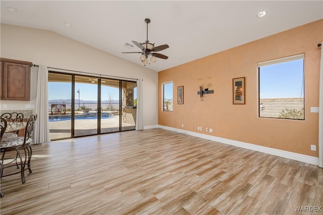 unfurnished room featuring lofted ceiling, light wood finished floors, and baseboards