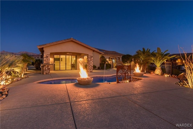 view of front of property featuring ceiling fan, an outdoor fire pit, a fenced in pool, stucco siding, and a patio area