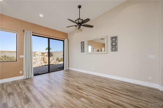 empty room with baseboards, lofted ceiling, a ceiling fan, and light wood-style floors