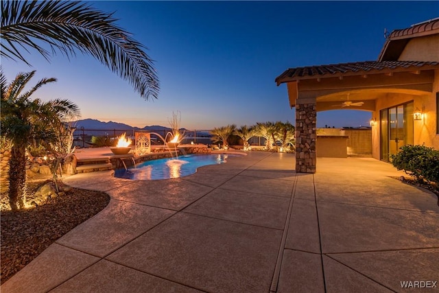 pool at dusk featuring a patio area, a ceiling fan, and an outdoor pool