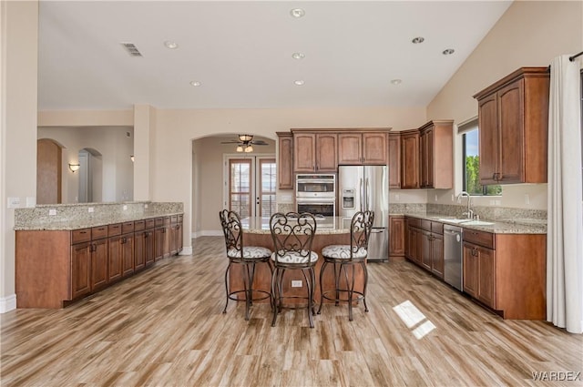 kitchen with visible vents, arched walkways, a breakfast bar area, light stone countertops, and stainless steel appliances