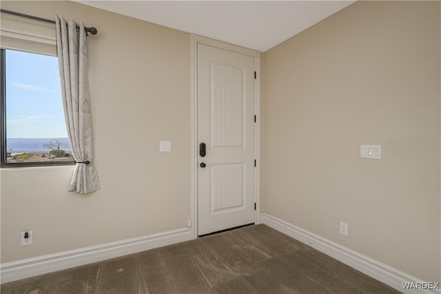 carpeted empty room featuring baseboards