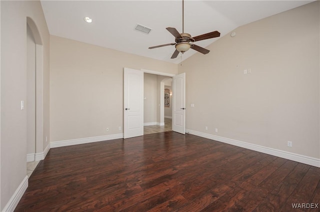 unfurnished room with lofted ceiling, arched walkways, wood finished floors, and visible vents