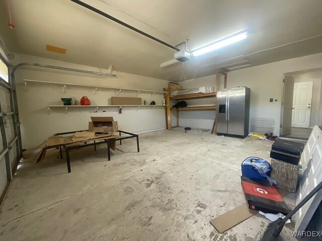 garage with stainless steel refrigerator with ice dispenser and a garage door opener