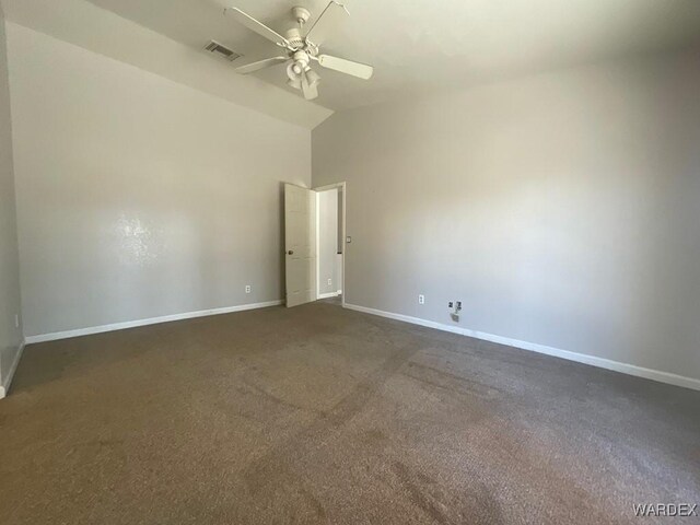 empty room with visible vents, dark carpet, a ceiling fan, vaulted ceiling, and baseboards