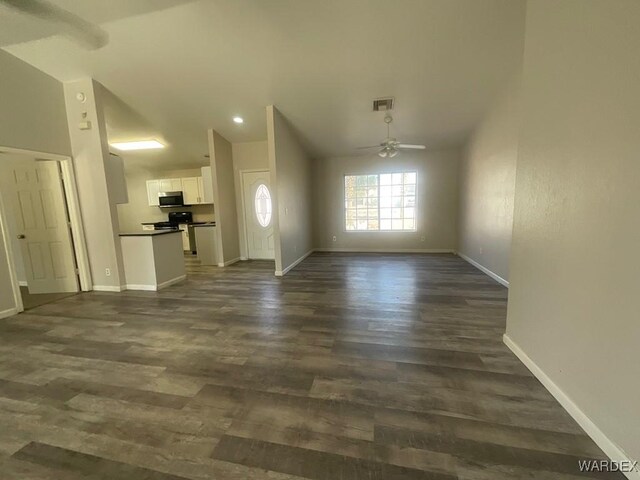 interior space with baseboards, visible vents, a ceiling fan, lofted ceiling, and dark wood-style floors