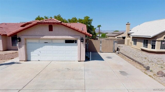 exterior space featuring a tiled roof, an attached garage, fence, and stucco siding